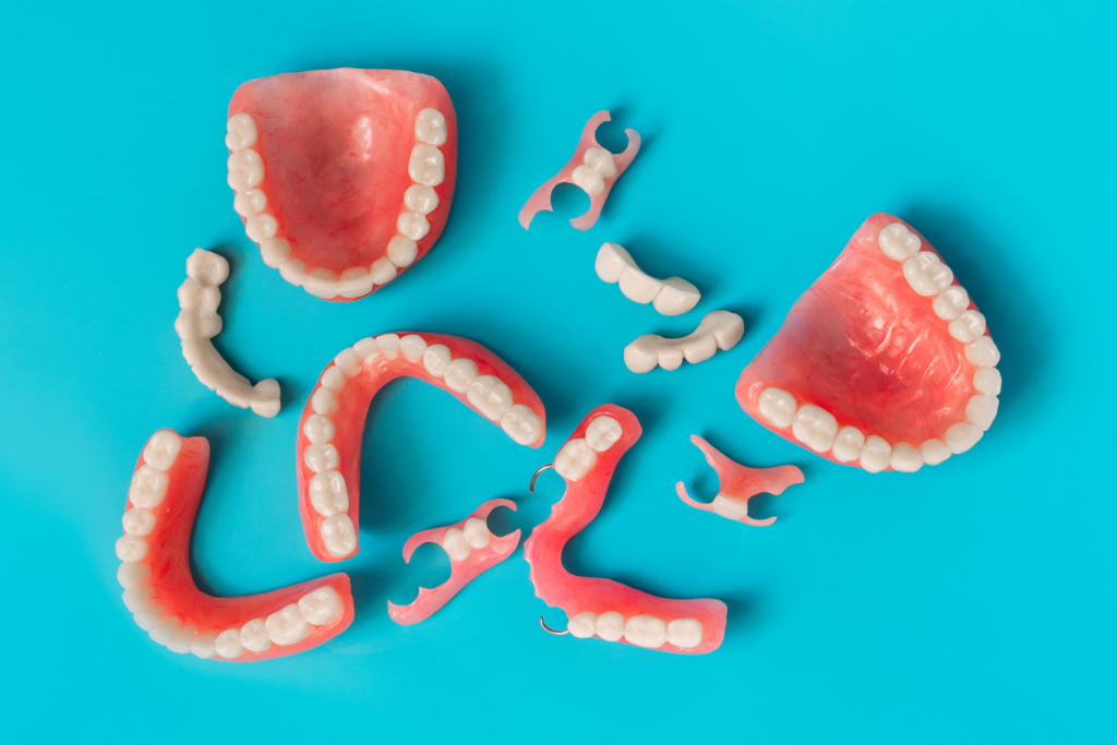 Top view of a set of dentures on a blue background, including a full denture, a partial denture, and an overdenture.